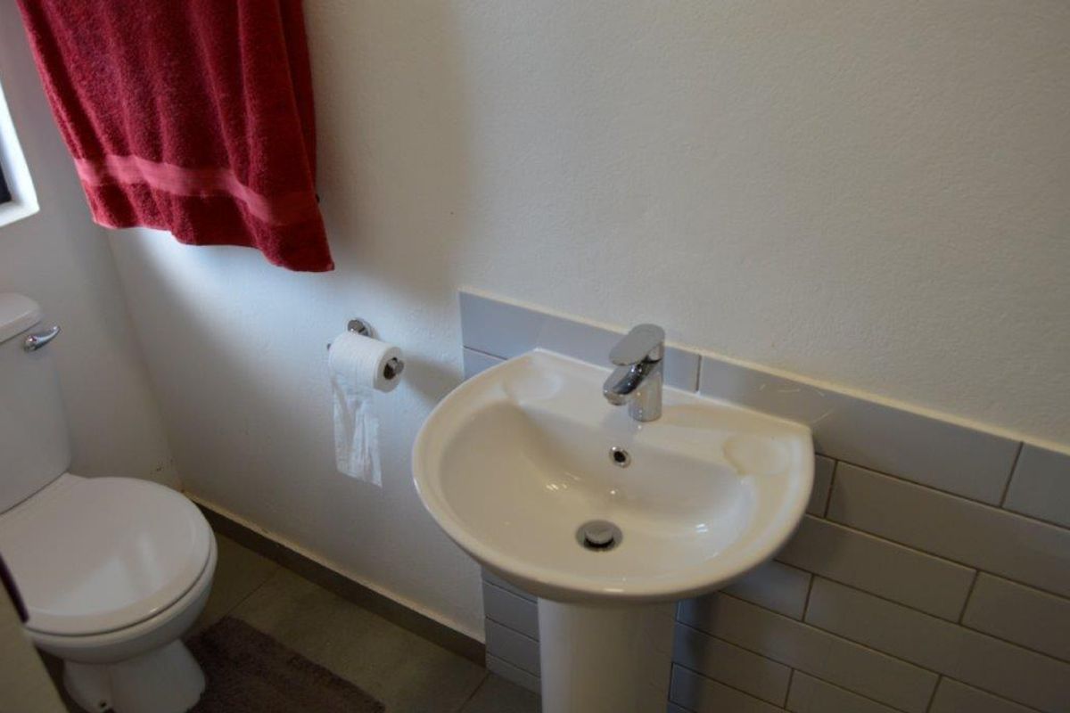 A functional bathroom featuring a white pedestal basin with chrome tapware and a standard toilet.