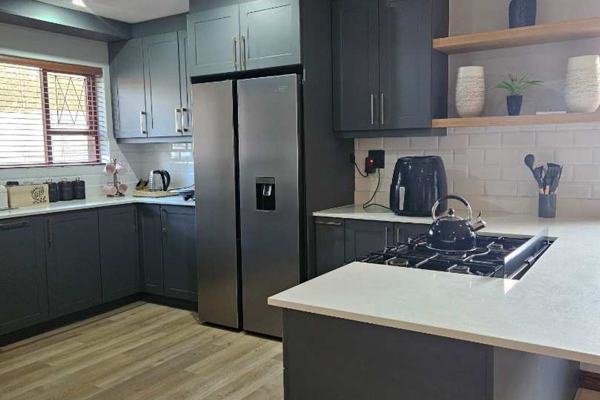 Modern kitchen featuring dark cabinetry, stone countertops, subway tile backsplash, gas cooktop, and floating timber shelving with integrated lighting.