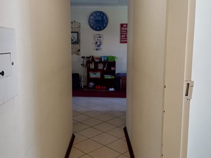 A functional hallway featuring tiled flooring and neutral walls, providing access to the living area.