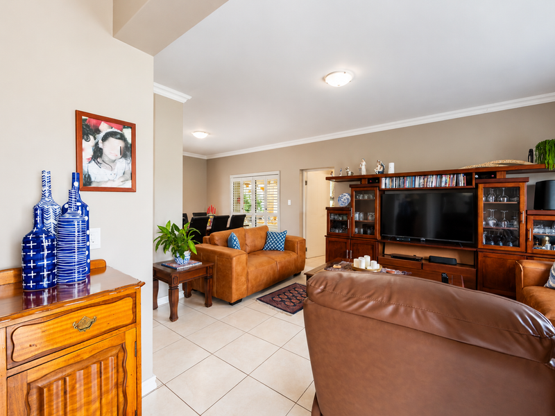 An open-plan living and dining area featuring neutral wall tones, tiled flooring, and crown molding, creating a cohesive and functional living space.