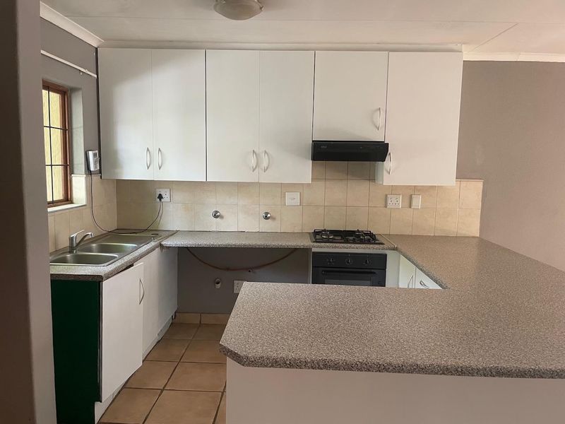 Functional kitchen featuring white cabinetry, laminate countertops, built-in oven, gas hob, and tiled backsplash, offering a practical layout for daily meal preparation.