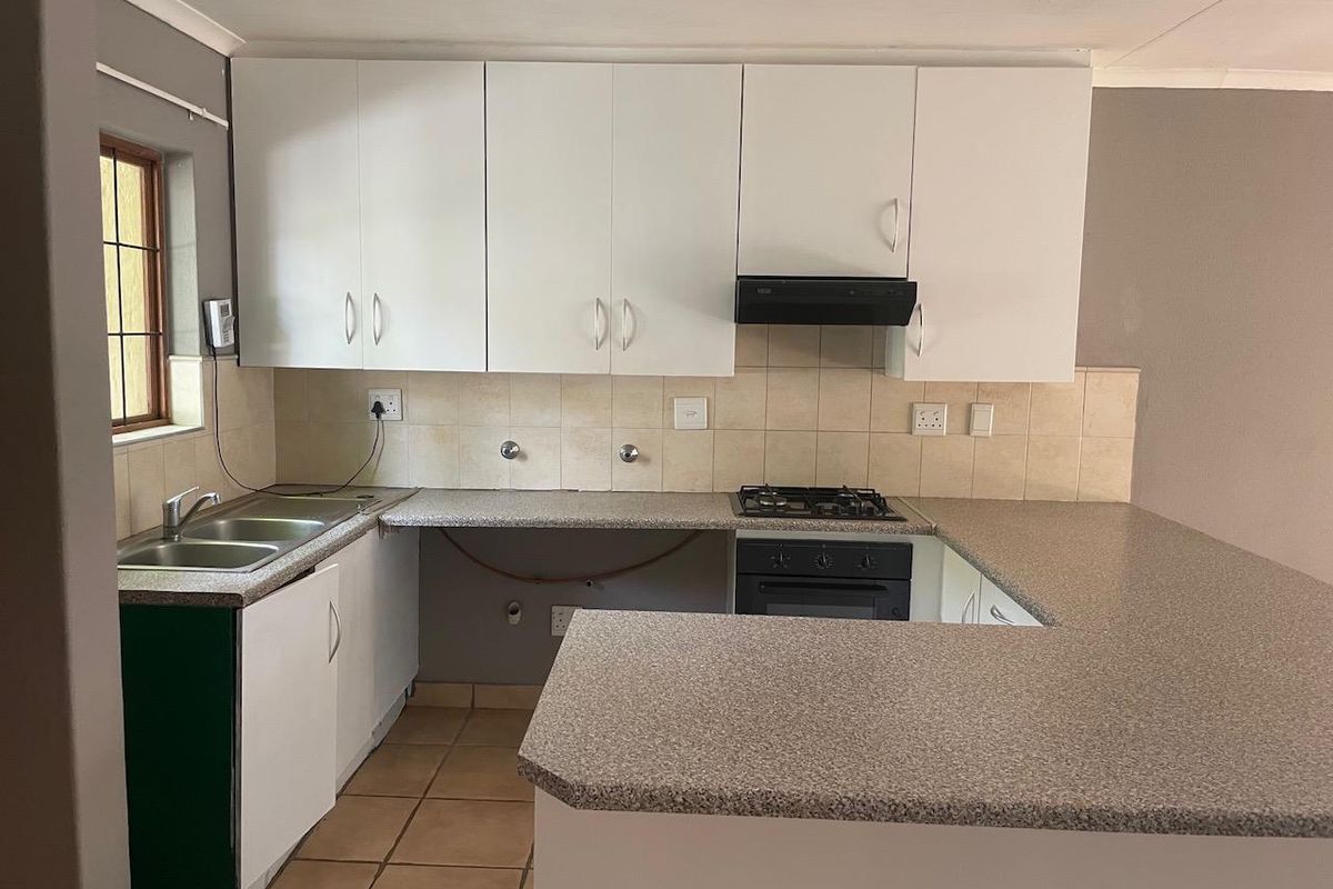 Functional kitchen featuring white cabinetry, laminate countertops, built-in oven, gas hob, and tiled backsplash, offering a practical layout for daily meal preparation.