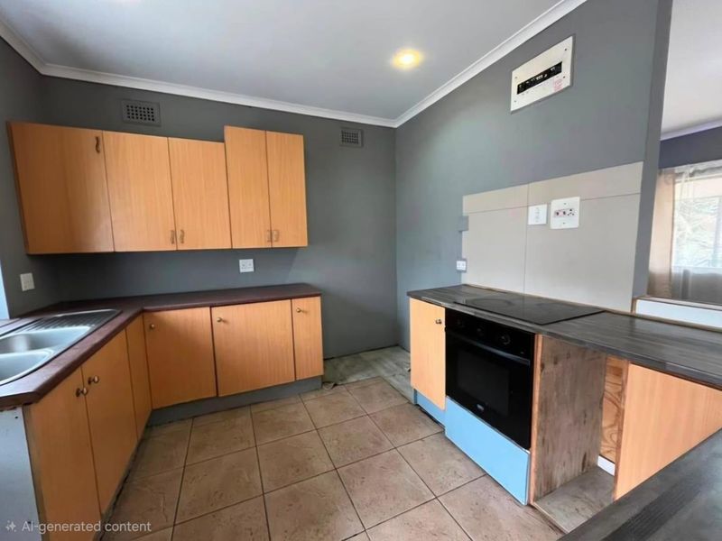A functional kitchen featuring wood-finish cabinetry, laminate countertops, and built-in cooking appliances, requiring minor finishing touches to the cabinetry base.
