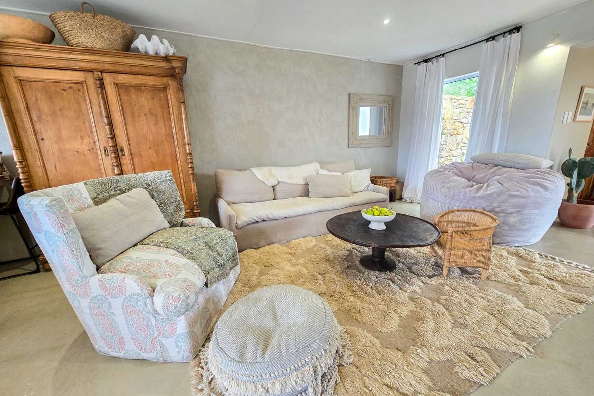 A comfortable living room featuring polished concrete flooring, recessed ceiling lighting, and large windows with sheer curtains allowing for natural light.
