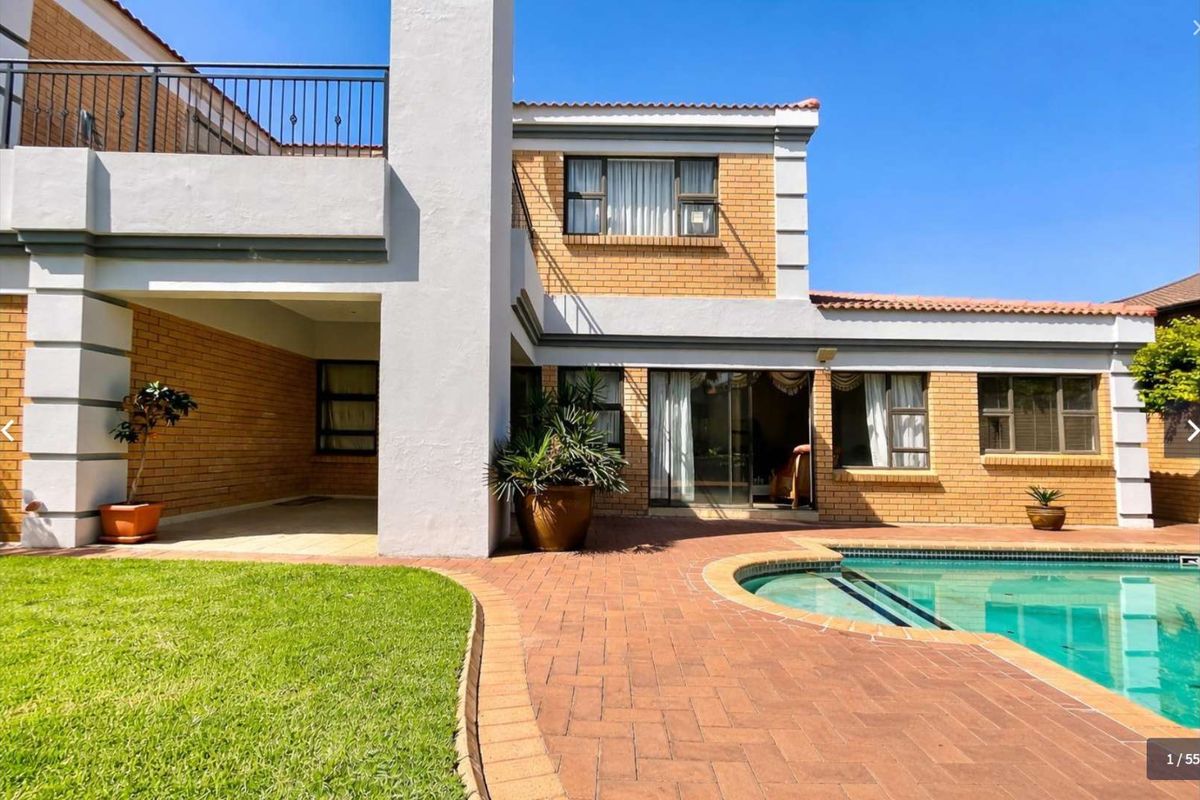 Rear view of the property featuring a swimming pool, brick-paved patio area, covered terrace, and a balcony with wrought iron railings.