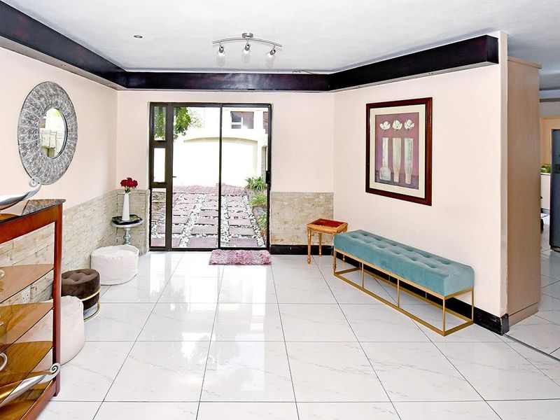 Bright entrance hall featuring polished porcelain floor tiles, stone wall accents, and a sliding glass door providing direct access to the exterior.