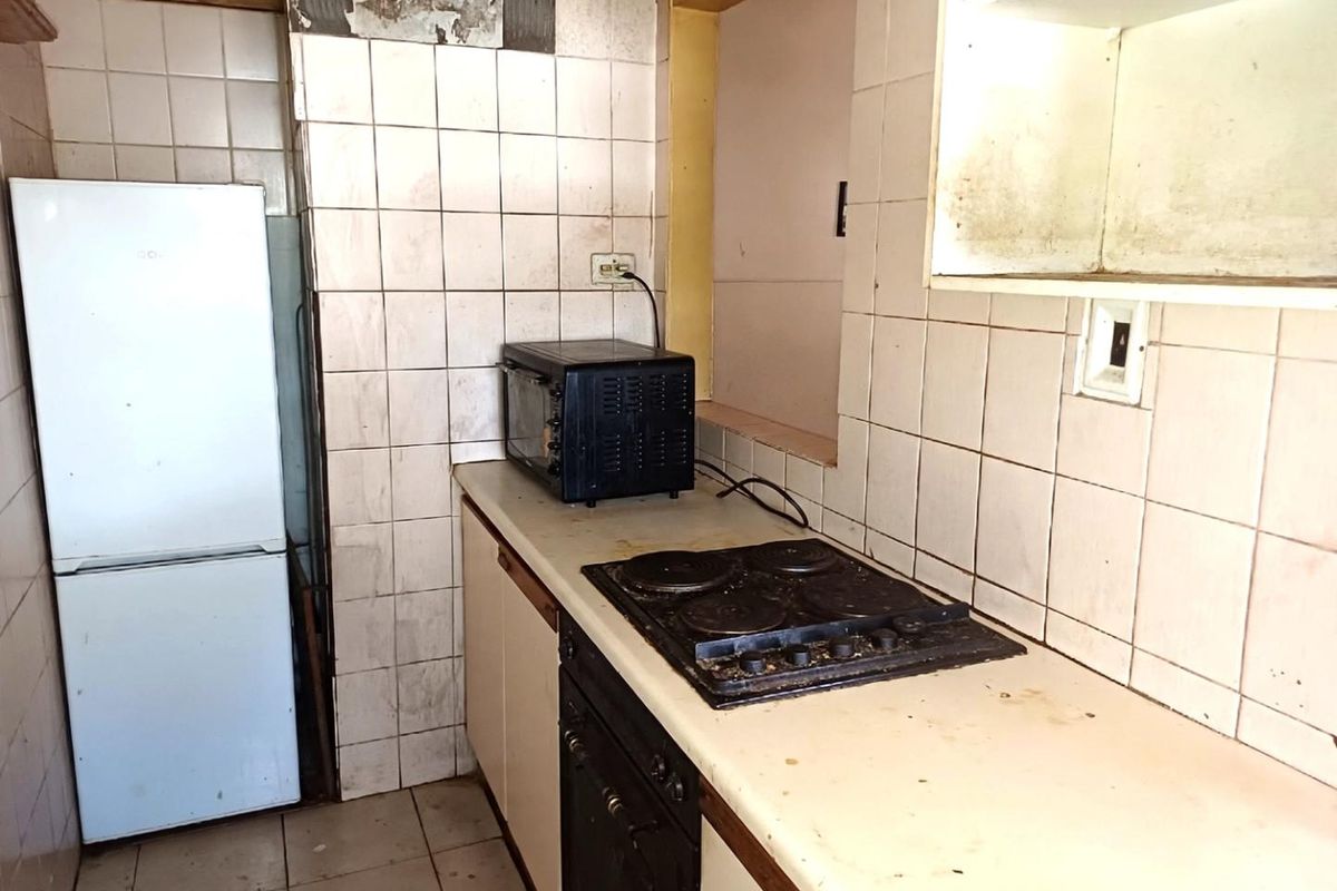 A dated kitchen featuring built-in cabinetry, an electric hob, and an oven, requiring significant renovation and cosmetic updates to improve functionality and aesthetic appeal.
