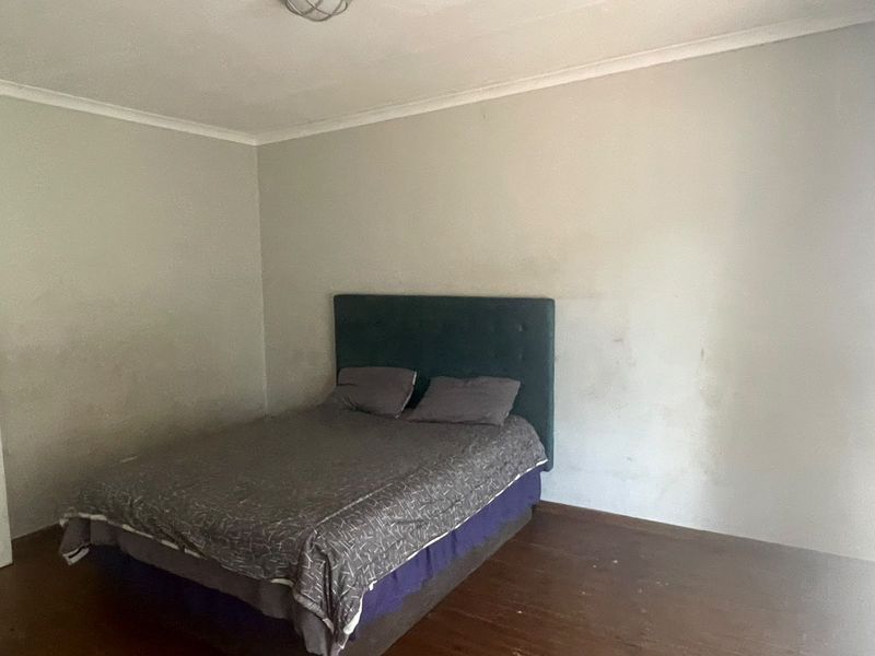 A bedroom featuring wooden flooring and plain walls, requiring cosmetic updates to improve the overall condition and appeal of the space.
