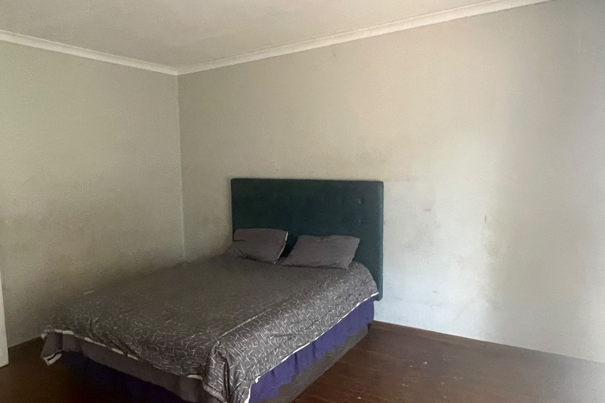 A bedroom featuring wooden flooring and plain walls, requiring cosmetic updates to improve the overall condition and appeal of the space.