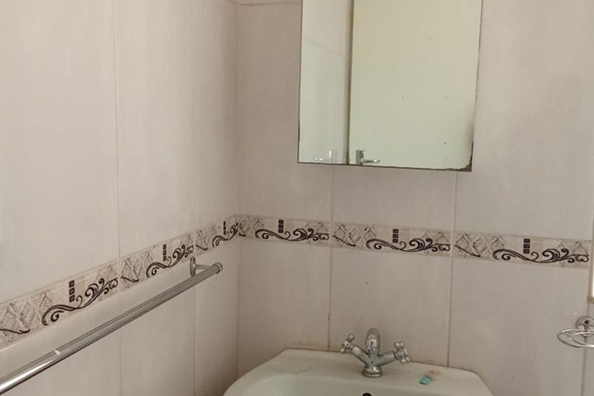 A functional bathroom featuring a pedestal basin, chrome fixtures, and decorative wall tiling, currently requiring minor maintenance and cosmetic updates.