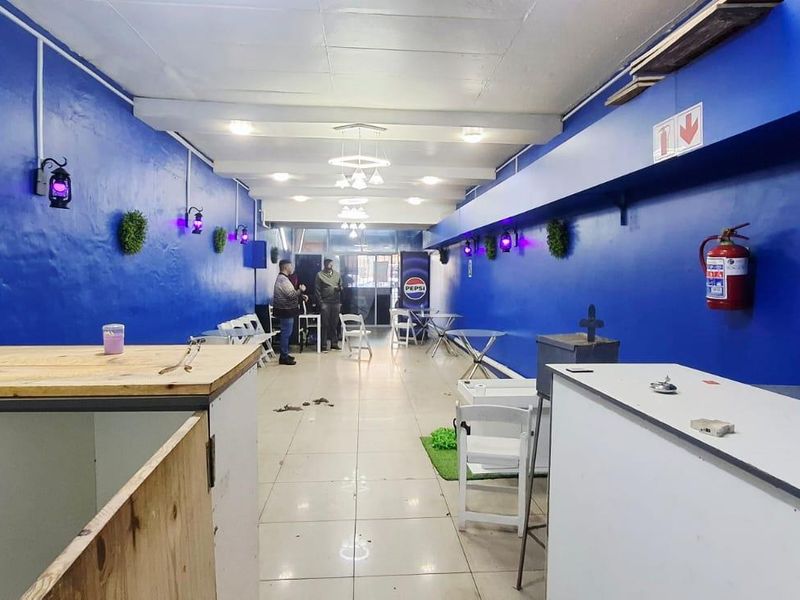 Open-plan commercial space featuring tiled flooring, bright blue walls, and integrated ceiling lighting, suitable for various business or retail applications.