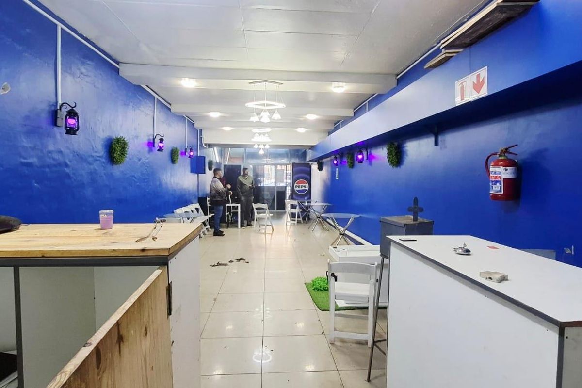 Open-plan commercial space featuring tiled flooring, bright blue walls, and integrated ceiling lighting, suitable for various business or retail applications.