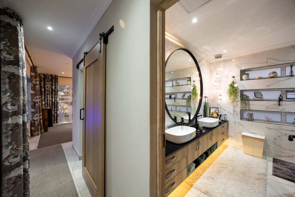 Modern bathroom featuring a double vanity with vessel sinks, marble-look wall tiles, recessed shelving, and a sliding barn door entrance.