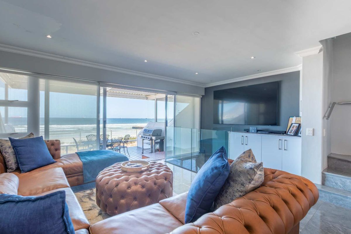 Spacious living area featuring large sliding glass doors that open onto a balcony with stunning ocean views and integrated cabinetry.
