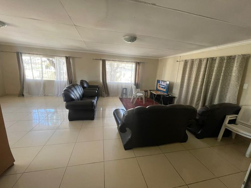 Spacious living room featuring large format floor tiles and a tiled ceiling, offering a blank canvas for interior updates.