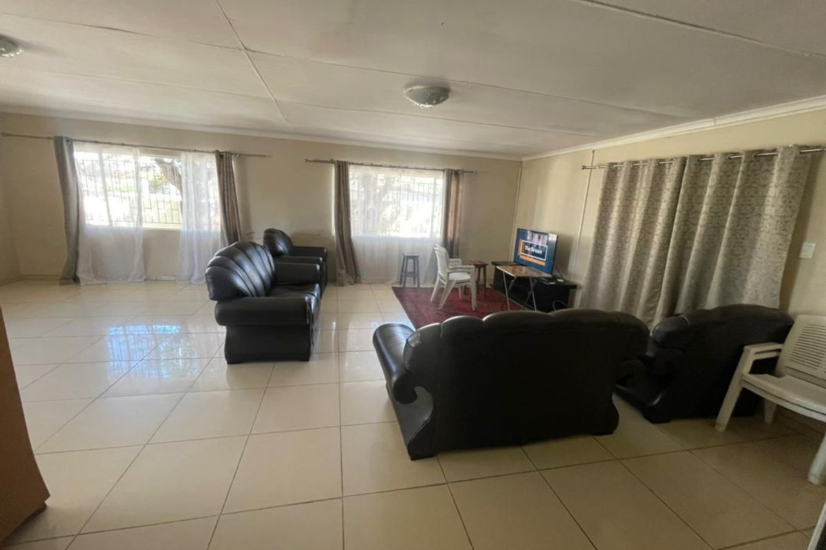 Spacious living room featuring large format floor tiles and a tiled ceiling, offering a blank canvas for interior updates.