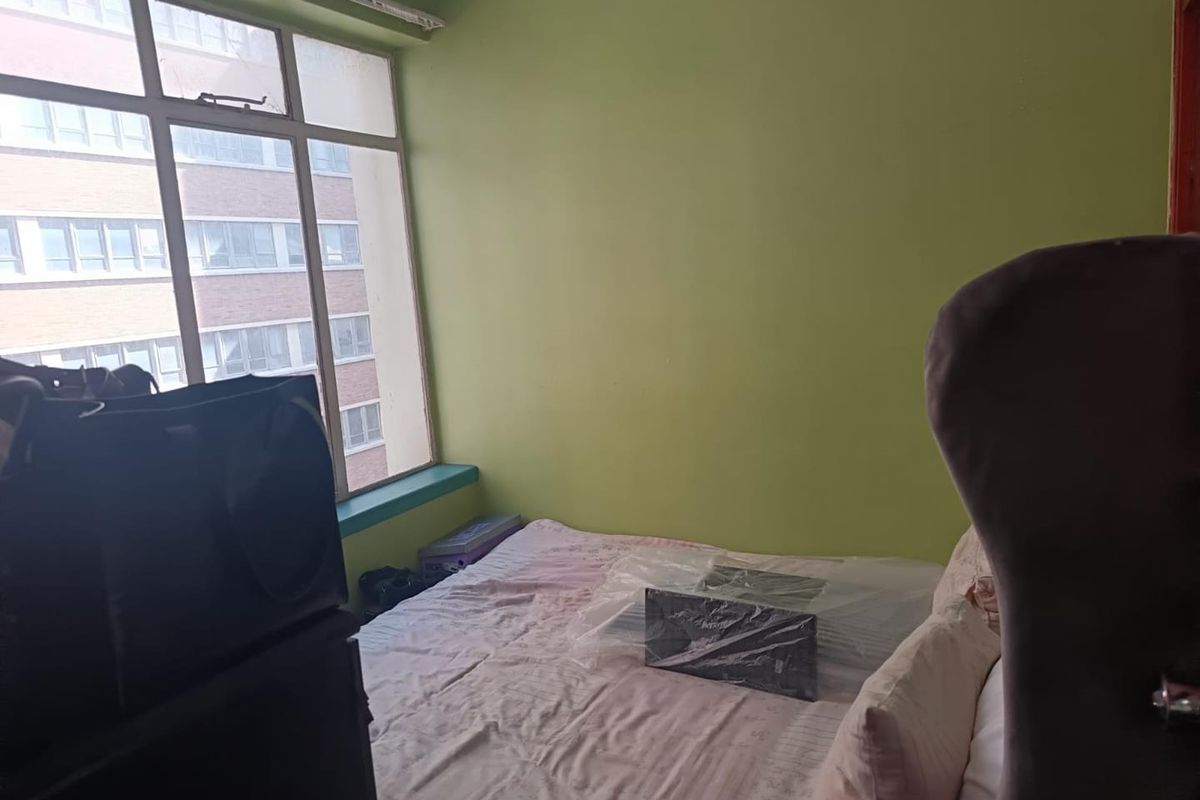 A bedroom featuring a large multi-pane window that provides natural light and an urban view.