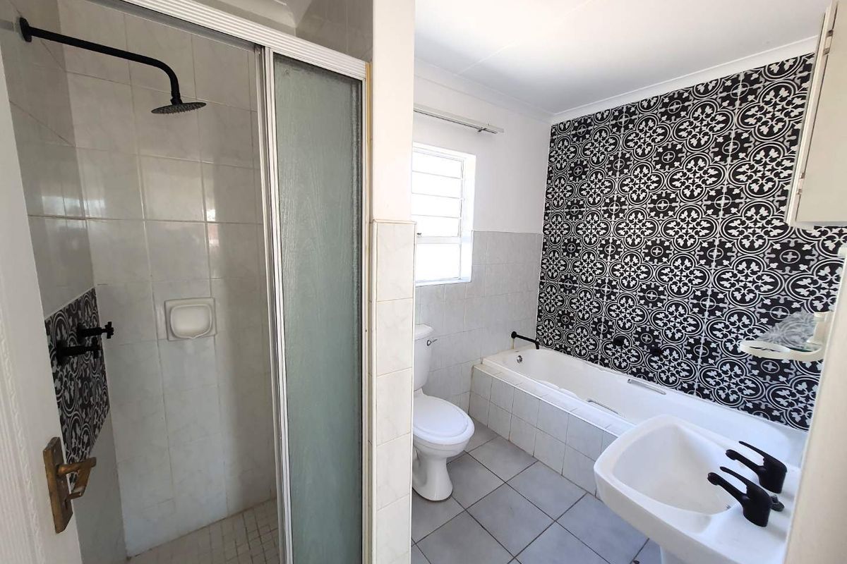 A bathroom featuring a separate shower enclosure, a bathtub with decorative patterned wall tiles, a pedestal basin, and a toilet.