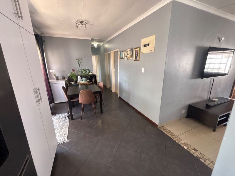 Open plan living and dining area featuring dark tiled flooring, coved ceilings, and built-in storage cabinetry.