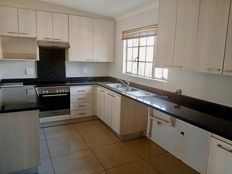 A functional kitchen featuring granite countertops, built-in oven, electric hob, and ample laminate cabinetry. The space is clean and ready for personalization.