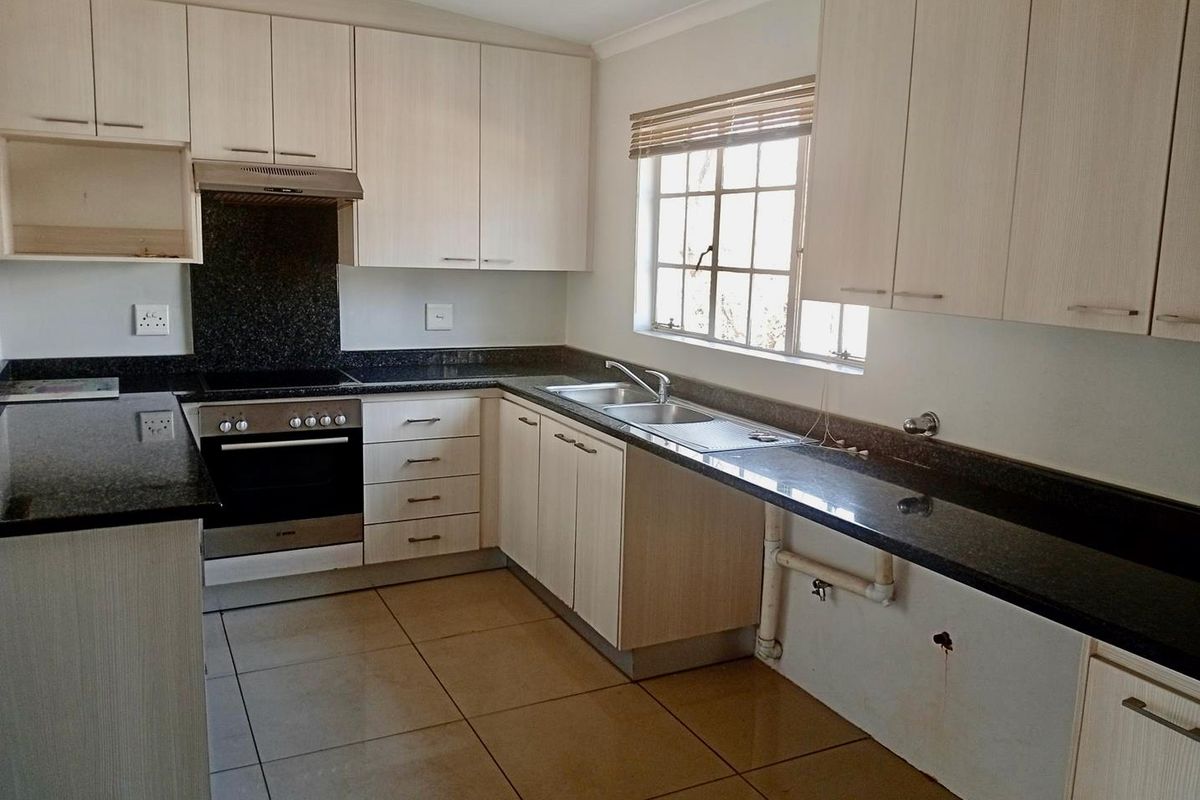 A functional kitchen featuring granite countertops, built-in oven, electric hob, and ample laminate cabinetry. The space is clean and ready for personalization.