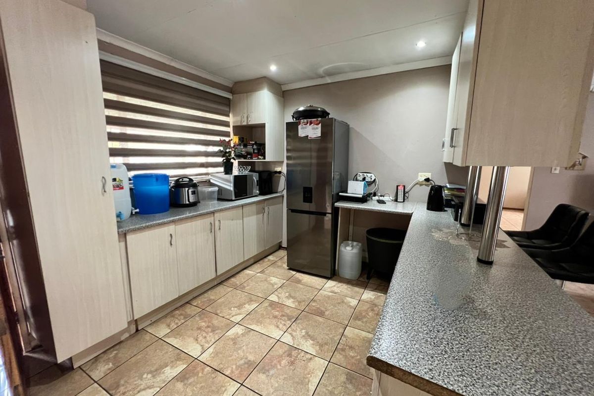 A functional kitchen featuring laminate cabinetry, granite-look countertops, and ceramic floor tiles, illuminated by recessed downlights.