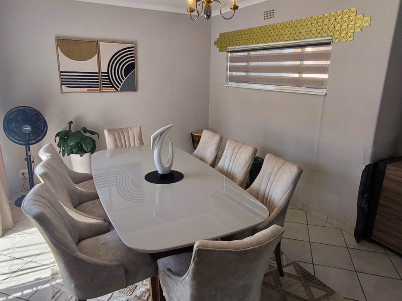 A well-maintained dining room featuring tiled flooring, cove cornicing, and modern roller blinds, providing a functional and comfortable space for family meals.
