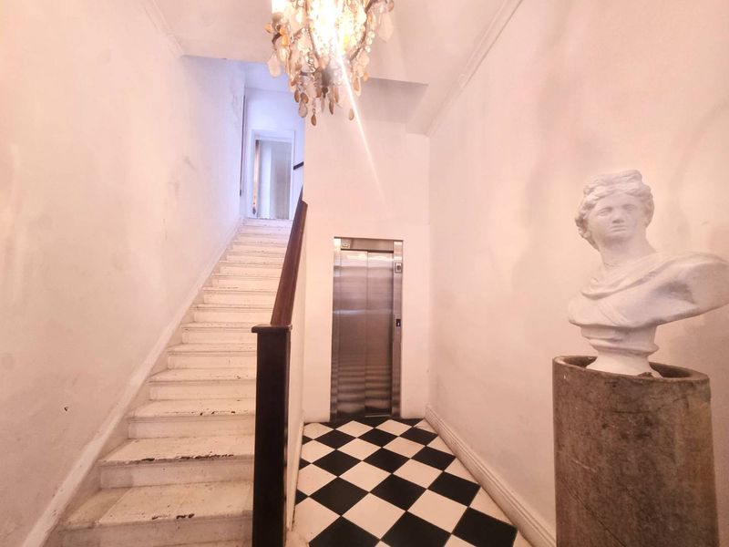 Entrance foyer featuring a classic staircase with wooden handrail, a modern elevator, and distinctive black and white checkered tile flooring.