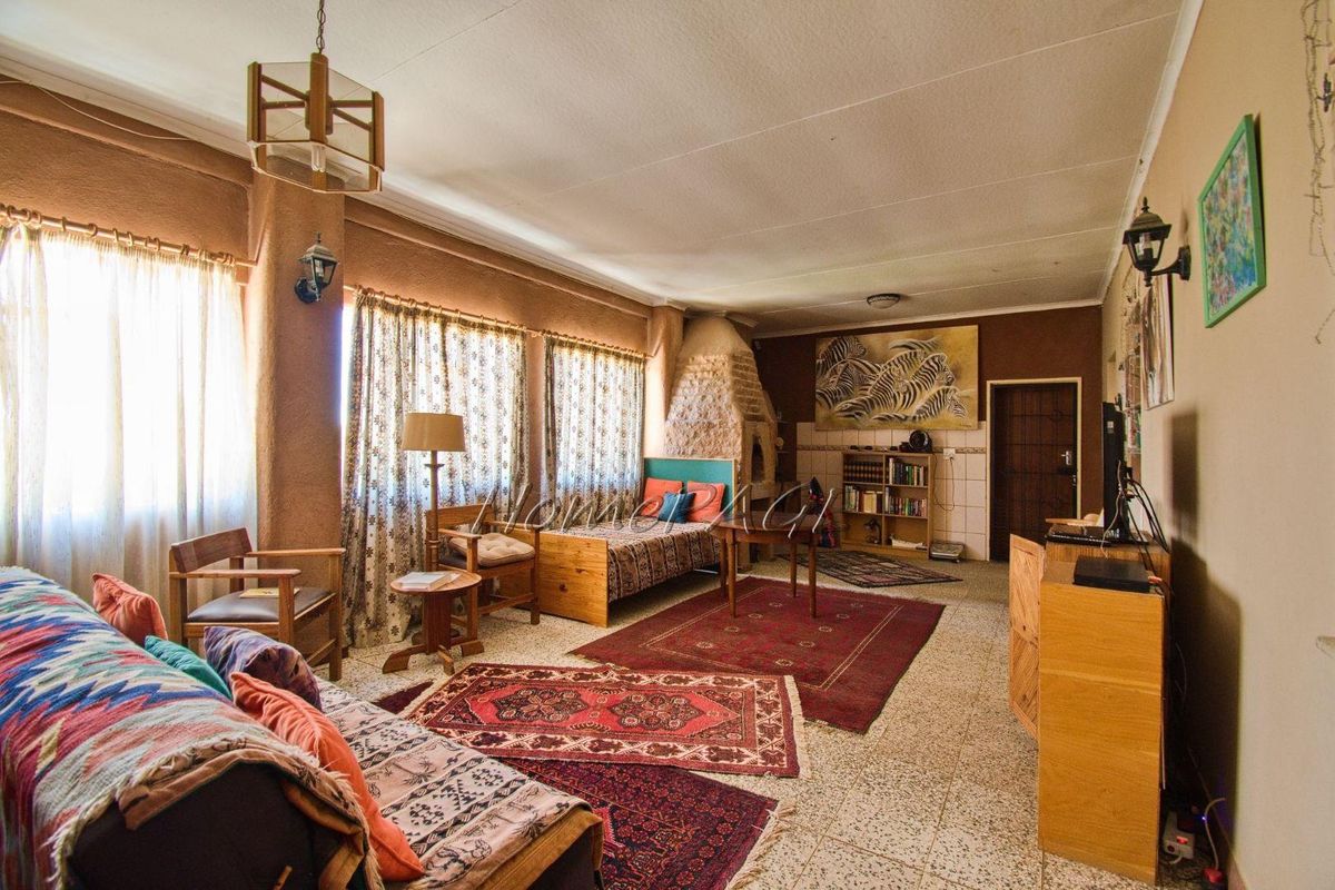 Spacious living room featuring a prominent stone-clad fireplace, tiled flooring, and large windows allowing for ample natural light.