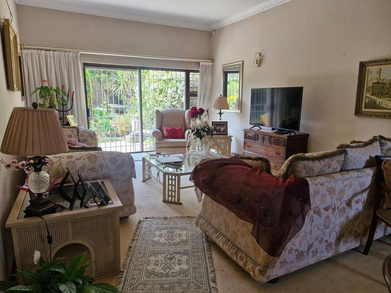 A comfortable living room featuring a sliding glass door with security gate, providing access to the outdoor area and natural light.