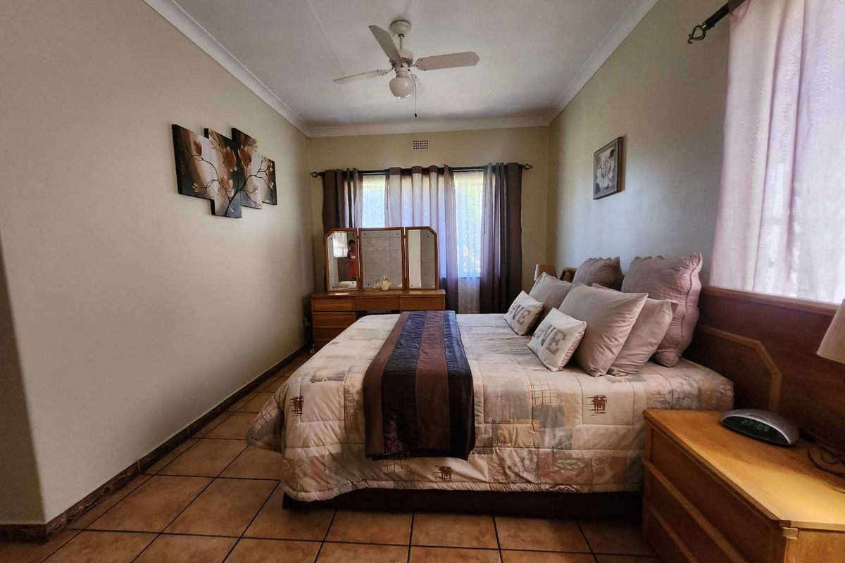 A well-proportioned bedroom featuring tiled flooring, coved cornicing, and a ceiling fan, offering a functional space ready for modern updates.