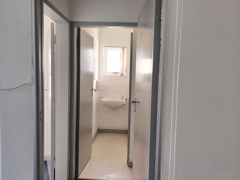 A functional hallway area featuring a small wash basin and clear fire safety signage, providing access to adjacent rooms.