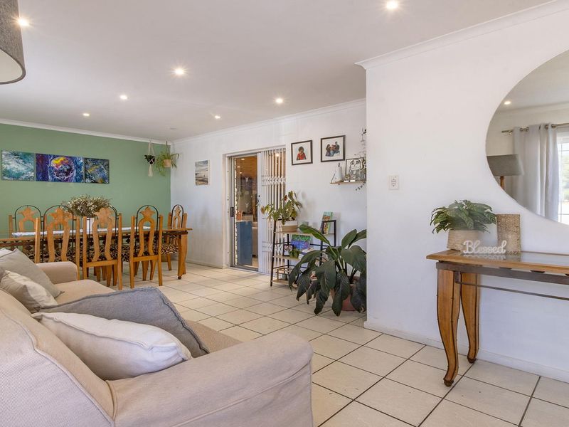 Open plan living and dining area featuring tiled flooring, recessed downlights, and a sliding glass door leading to the exterior.