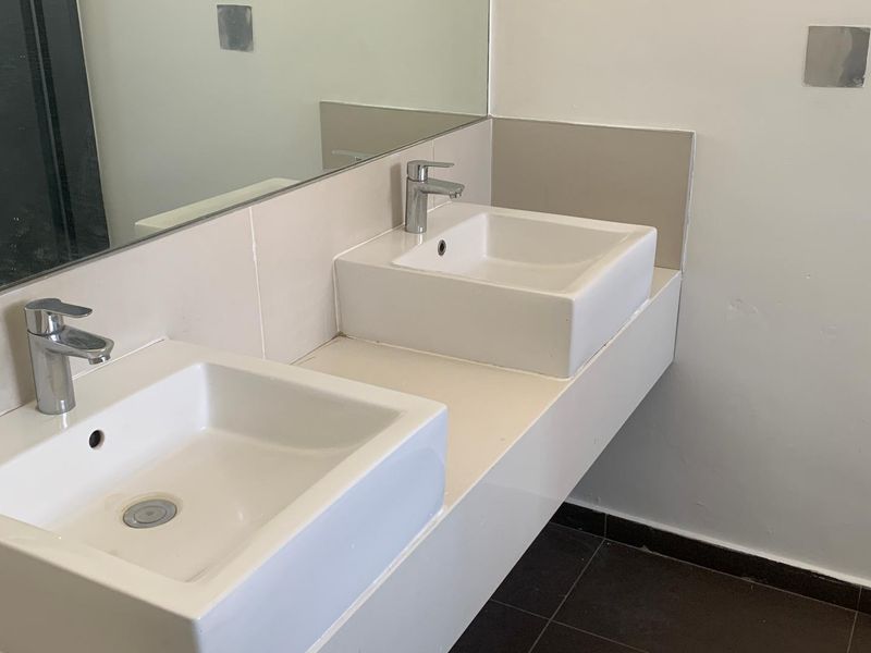 A functional bathroom featuring a double vanity with ceramic basins, chrome mixer taps, and a large wall-mounted mirror.