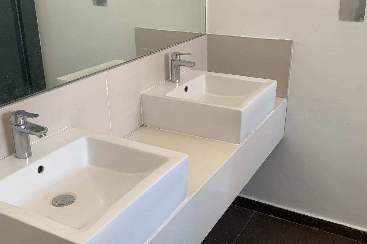 A functional bathroom featuring a double vanity with ceramic basins, chrome mixer taps, and a large wall-mounted mirror.
