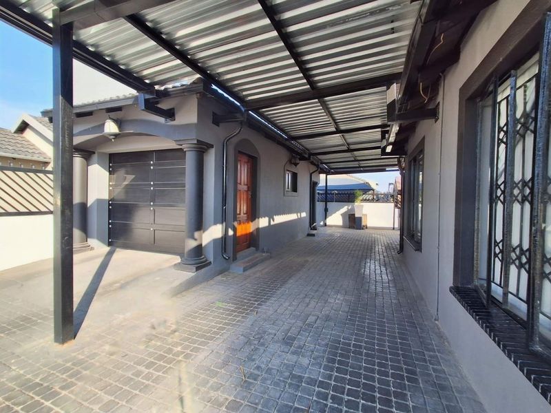 A well-maintained exterior view featuring a paved driveway, a covered carport, and a secure garage entrance with modern finishes.