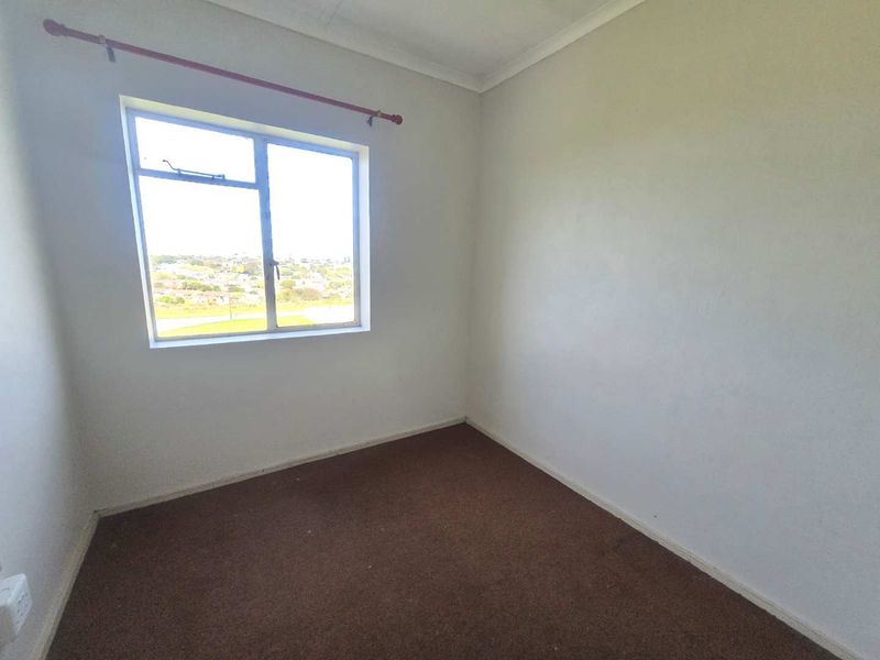 An empty bedroom featuring carpeted flooring, a window with a curtain rod, and neutral walls, offering a blank canvas for personalization.