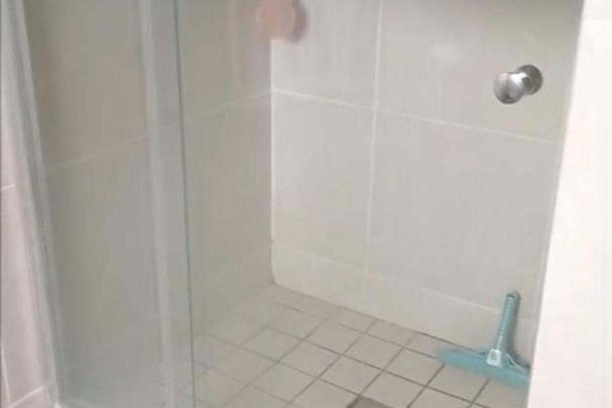 A functional bathroom shower area featuring a glass enclosure, tiled flooring, and wall tiling.