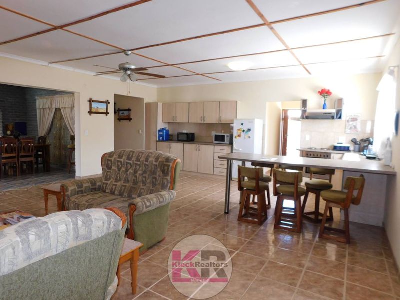 Open-plan living and kitchen area featuring tiled flooring, a breakfast bar, and functional built-in cabinetry with integrated cooking appliances.