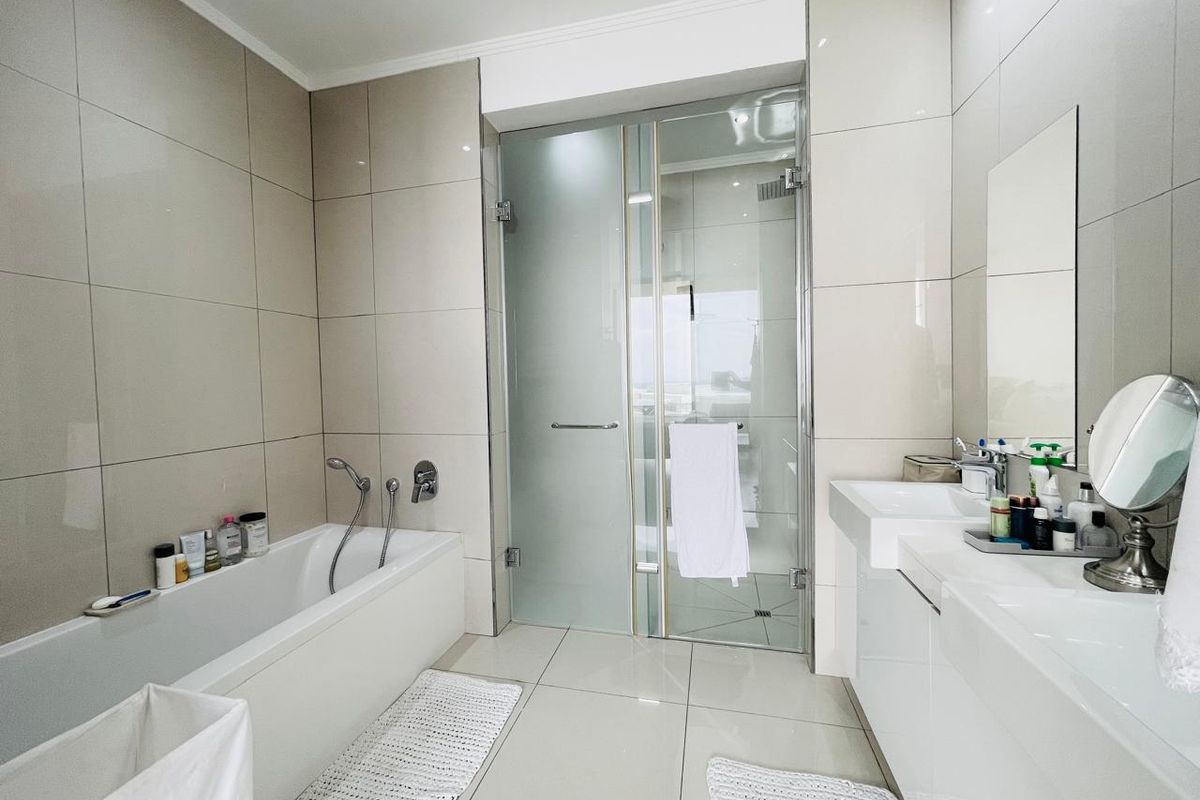 Modern bathroom featuring a built-in bathtub, a separate glass-enclosed shower, and a sleek double vanity with integrated sinks and large wall-mounted mirror.