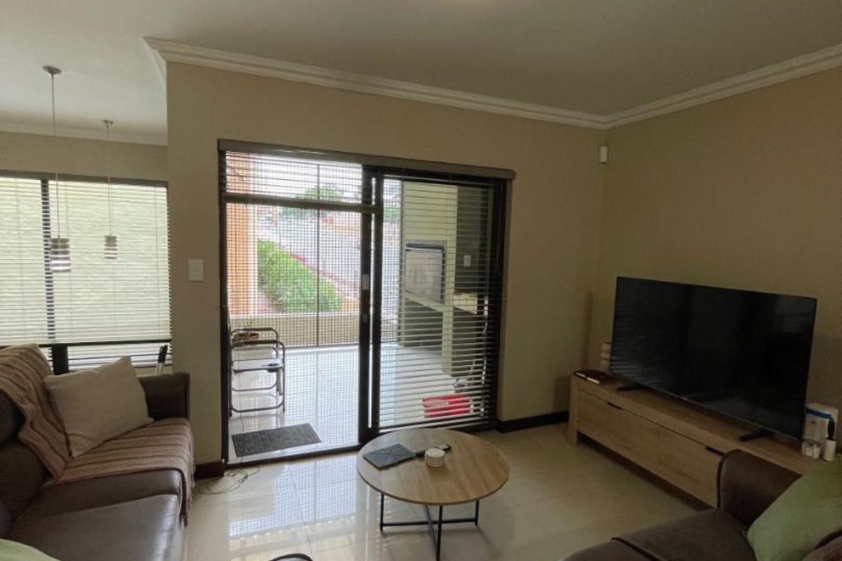 A comfortable living room featuring tiled floors, neutral walls, and a sliding glass door that provides direct access to an outdoor patio area.