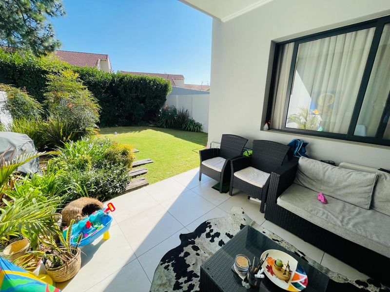 A covered patio area featuring tiled flooring and direct access to a private garden, providing a seamless transition between indoor and outdoor living spaces.