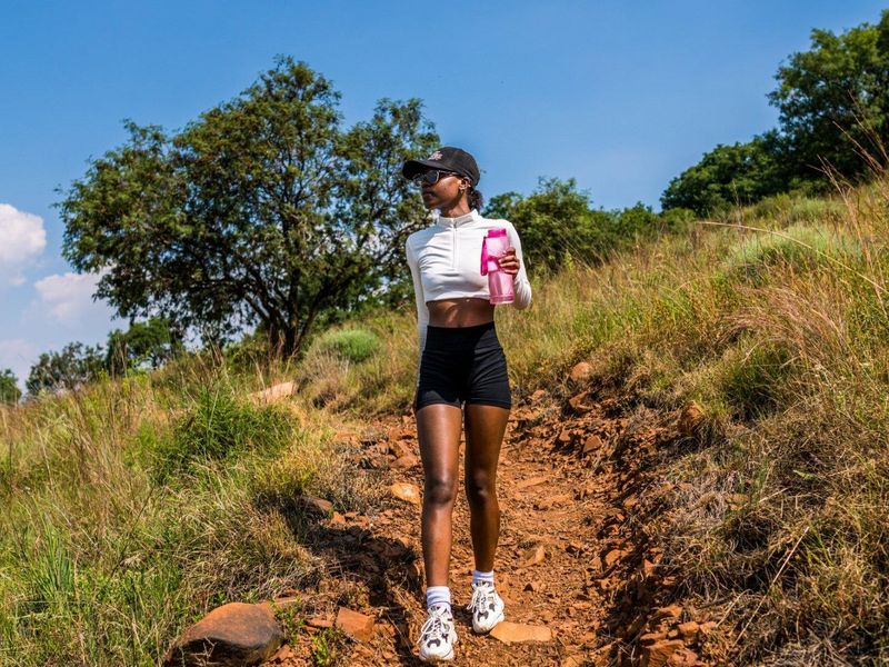 A person walking on a natural dirt trail in a grassy outdoor environment.