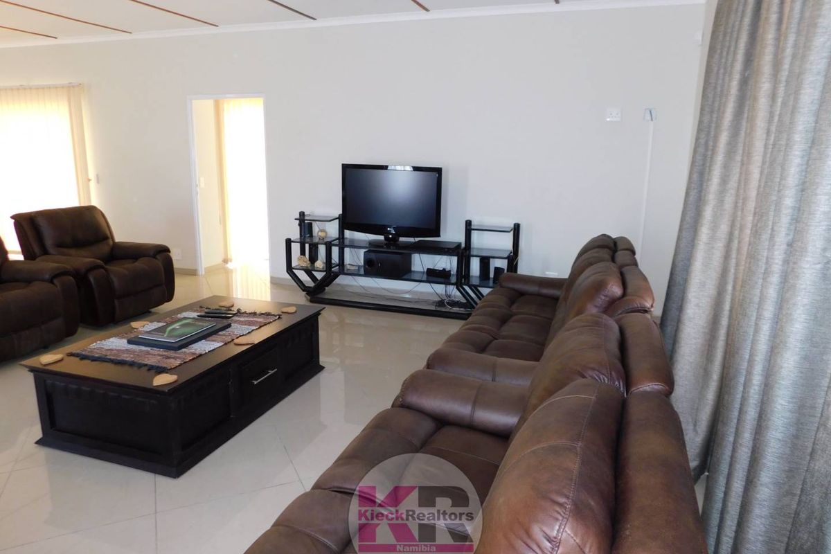 A spacious living room featuring polished tiled flooring and a coved ceiling, providing a comfortable and well-maintained area for relaxation.