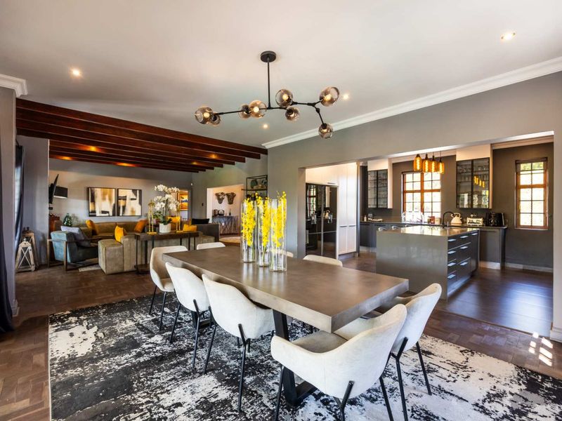 Spacious open-plan living and dining area featuring exposed timber beams, modern kitchen island, and elegant parquet flooring, creating a sophisticated and cohesive interior space.