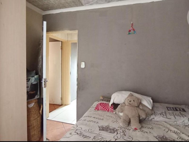 A bedroom featuring a built-in wardrobe and tiled flooring, currently requiring finishing work on the walls and ceiling.