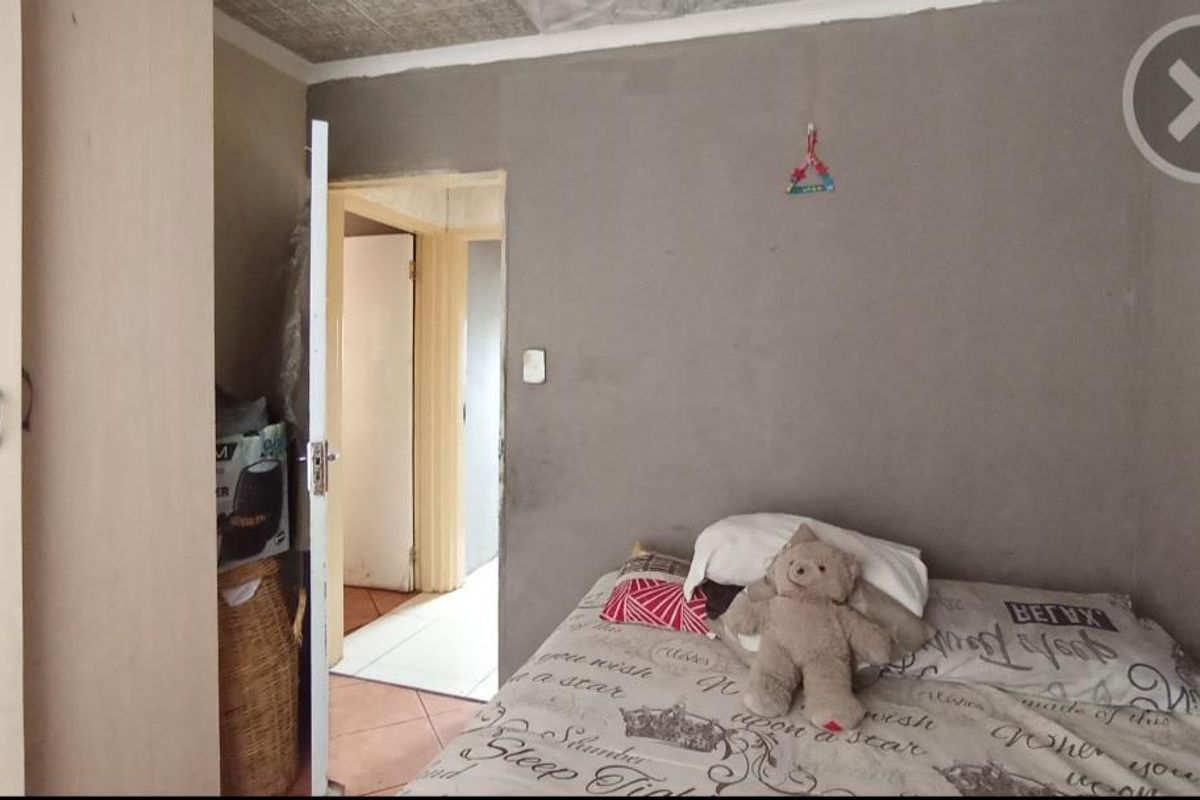 A bedroom featuring a built-in wardrobe and tiled flooring, currently requiring finishing work on the walls and ceiling.