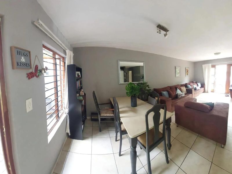 Spacious open-plan living and dining area featuring neutral tiled flooring and large windows with security bars, offering a functional layout for daily living.