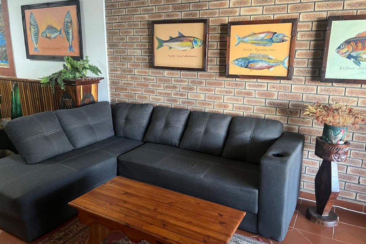 A living room area featuring a prominent exposed brick feature wall and terracotta-style floor tiles.