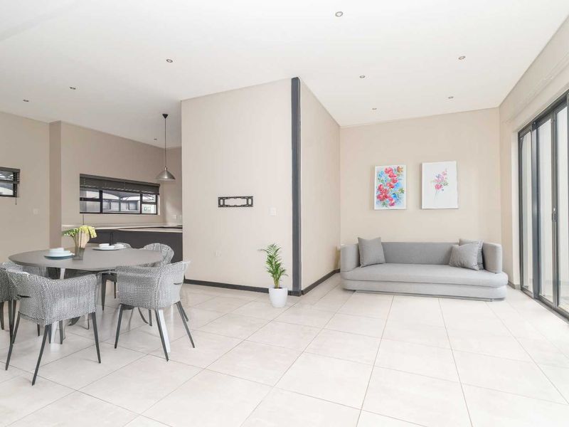 Spacious open-plan living and dining area featuring neutral tiled flooring, recessed lighting, and large sliding glass doors leading to the exterior.